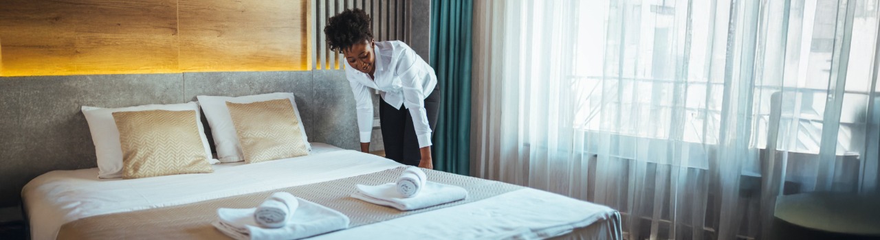 Une agente dentretien fait un lit dans une chambre dhôtel.