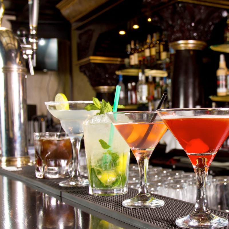 Divers cocktails sont disposés côte à côte sur un bar